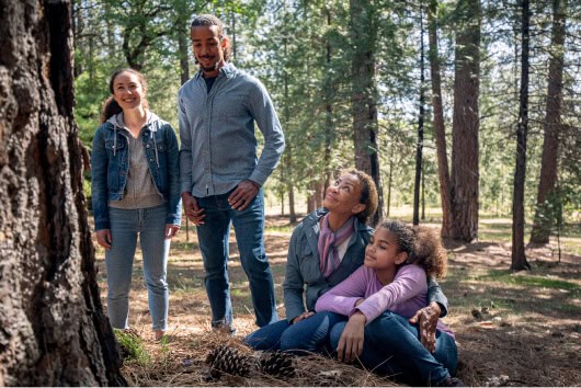 Family sits and stands at a Memorial Tree enjoying the Memorial Forest.