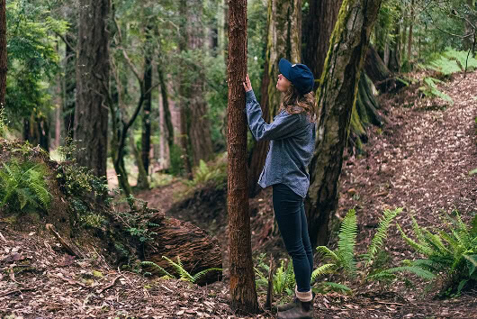 Woman standing next to a small but mighty Keepsake Memorial Tree.