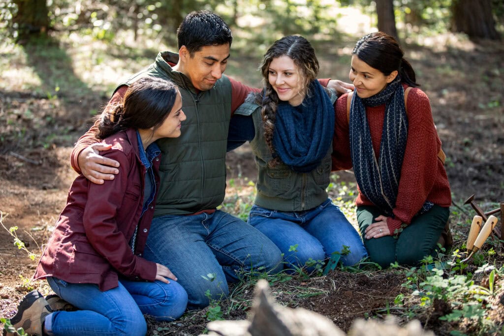 Family gathered at the base of a Memorial Tree in a Memorial Forest