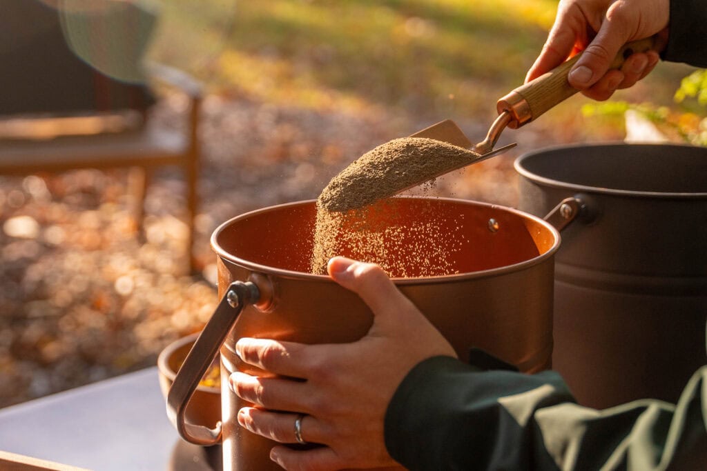 Guide mixing ashes with native soil in a vessel at a Forest Memorial ceremony