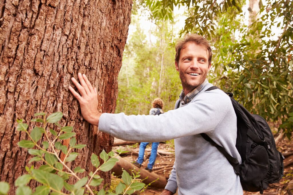 Father touching a Memorial Tree in a Memorial Forest, his son in the background