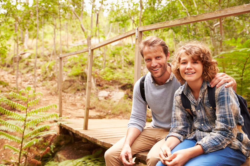 Father and son sitting on a bridge in a Memorial Forest