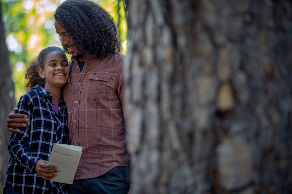 Family hugging at the base of a Memorial Tree after a Forest Memorial ceremony
