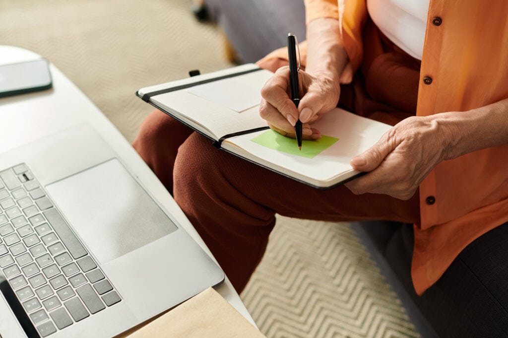 Senior woman enjoys a cozy moment at home while writing ideas in her notebook