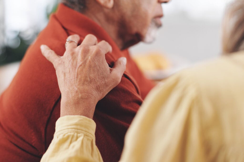 Elderly couple with hand on shoulder for support, empathy, or reassurance to partner with grief