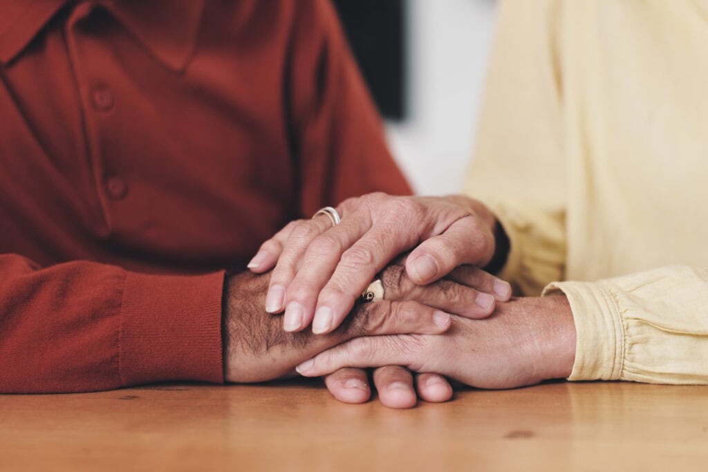 Elderly couple with holding hands for support, empathy and comfort to partner with grief