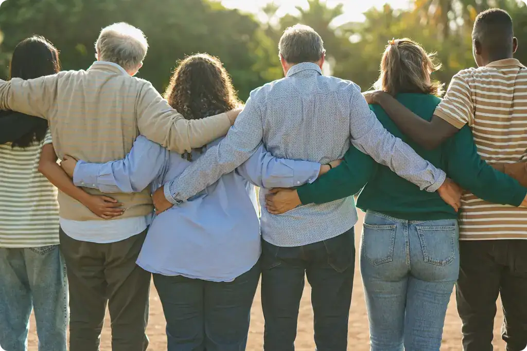 Back view of multigenerational community hugging each other in a Memorial Forest
