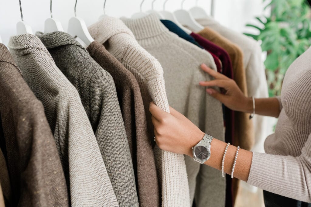 Hands of young female looking through closet of clothing