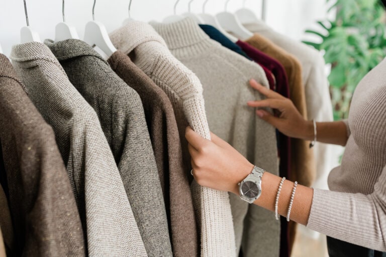 Hands of young female looking through closet of clothing
