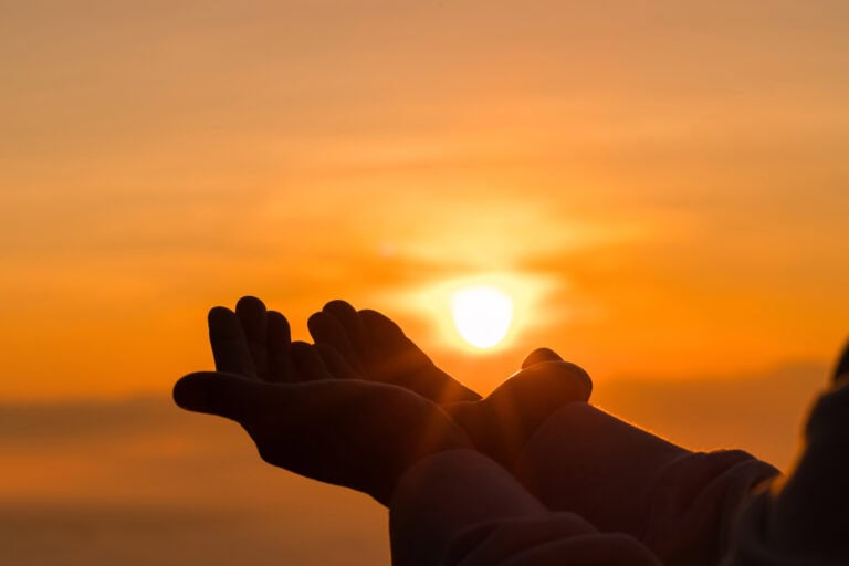 A moment of prayer at sunrise hands held open to the sky