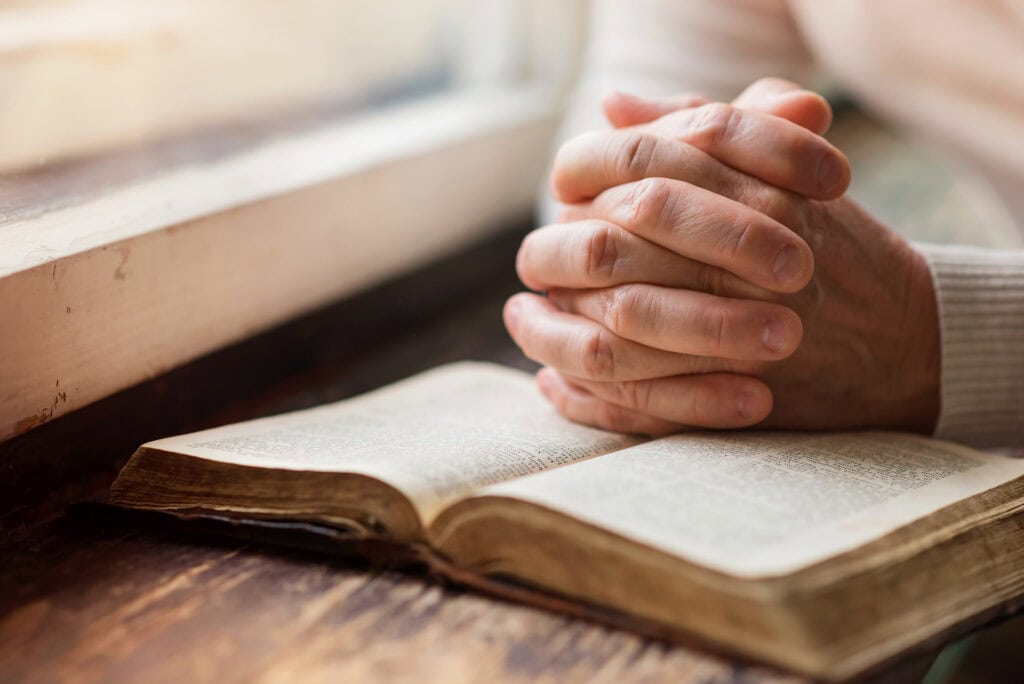 Woman's hands clasped with bible
