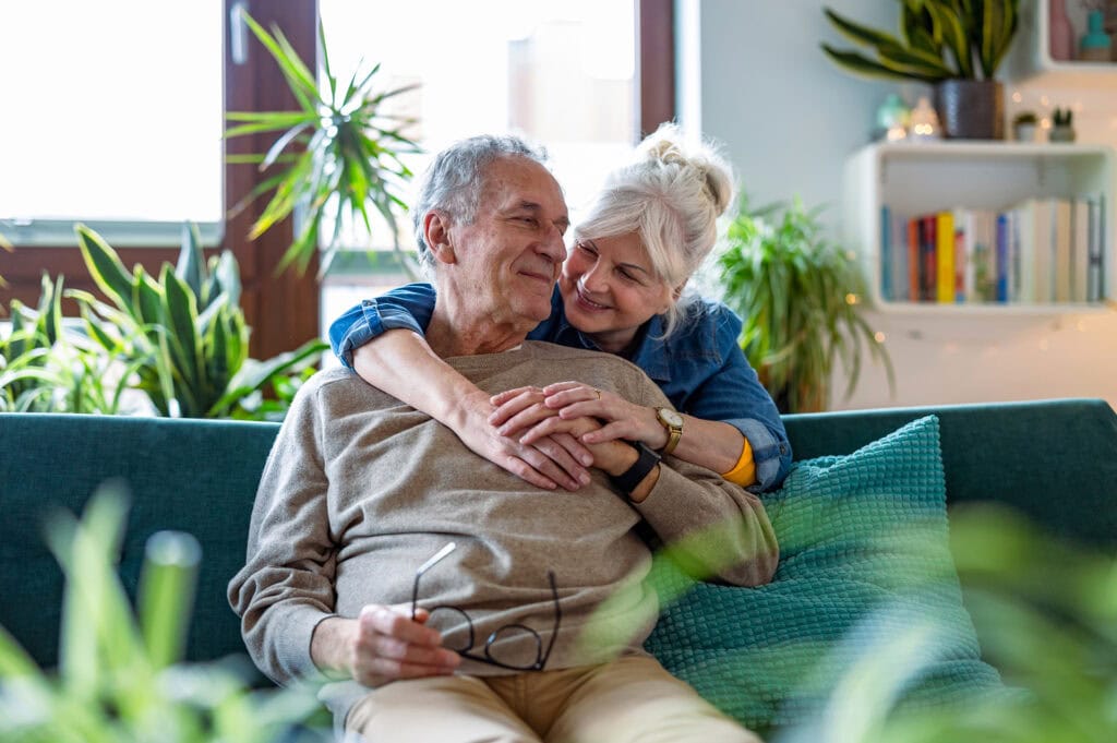 Happy senior couple sitting on sofa at home