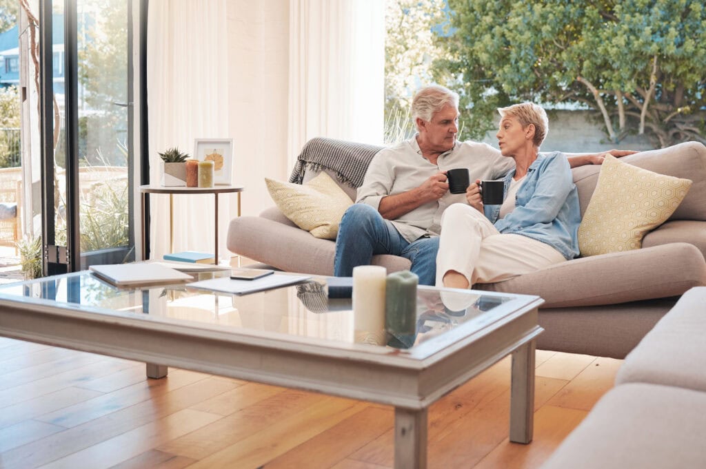 Elderly couple talking about end-of-life planning on a sofa, enjoying a peaceful morning in their living room together