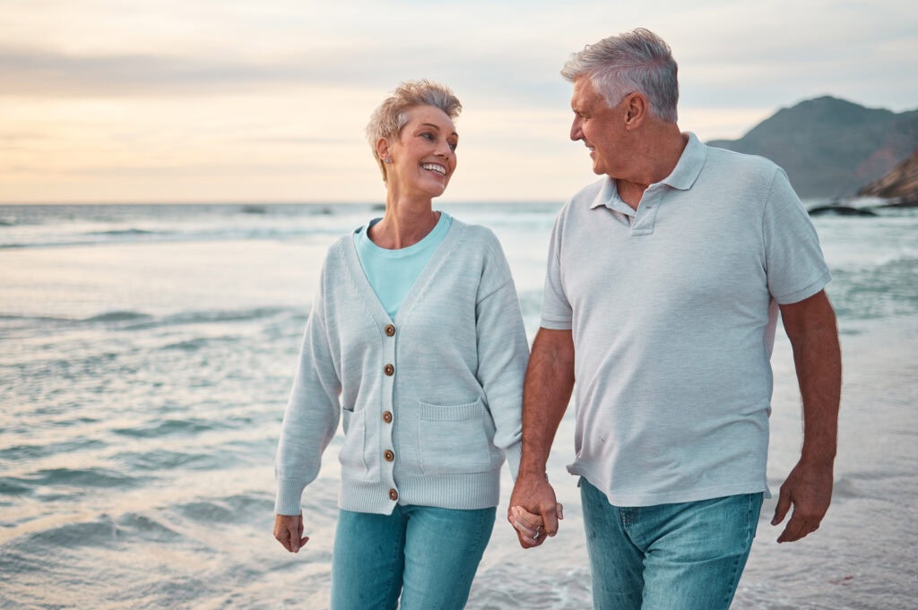 Happy elderly couple walking on the beach near the ocean