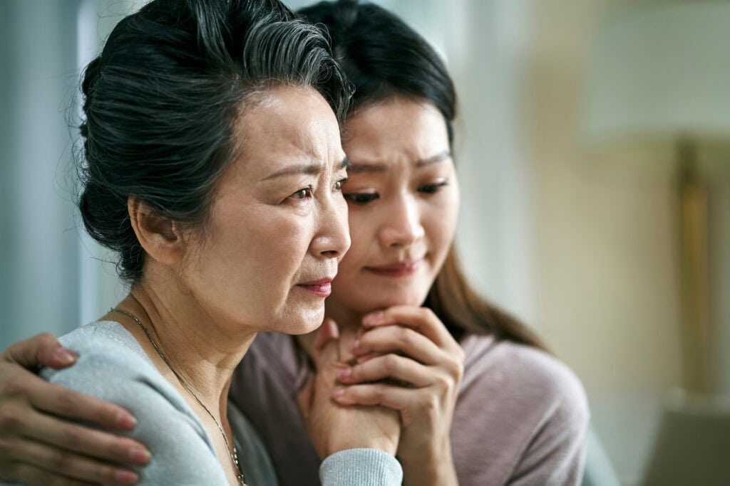 Grieving asian senior mother and adult daughter
