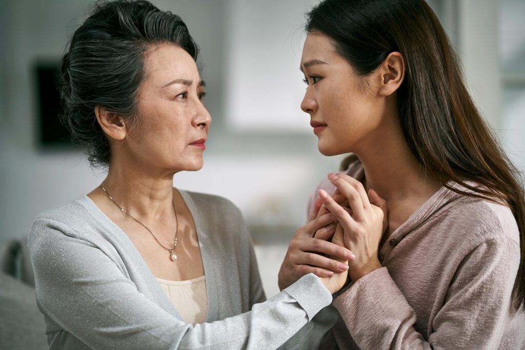 Young asian daughter comforting elderly mother