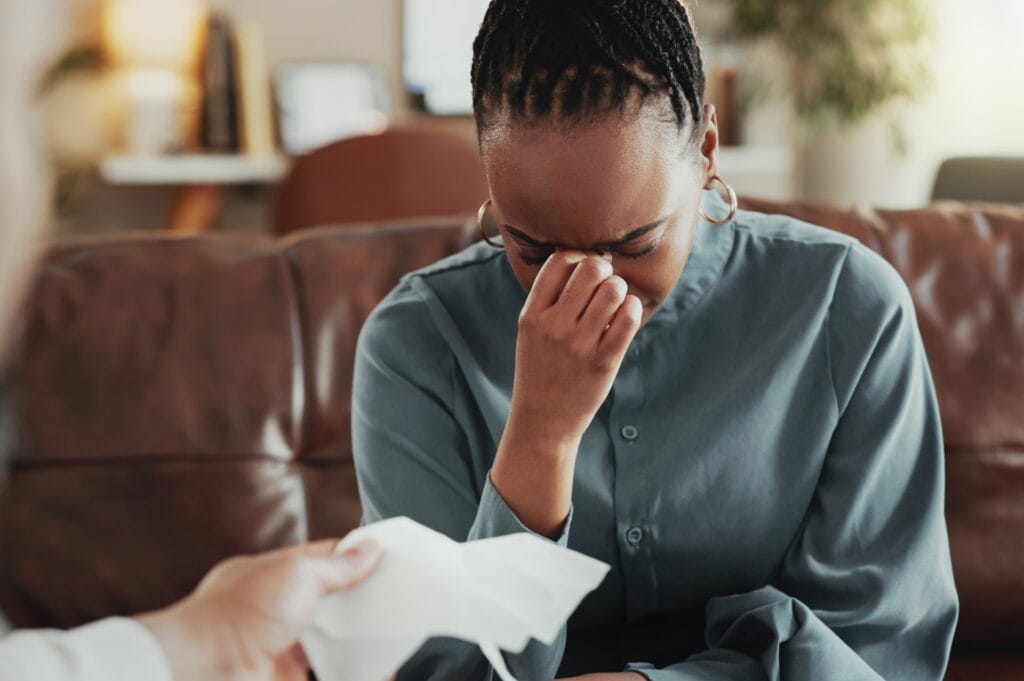 A woman cries as a man hands her a tissue