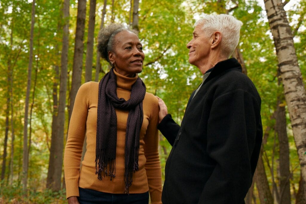 man puts hand on shoulder of a woman to comfort her in a memorial forest