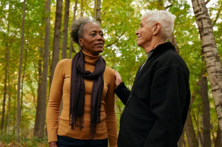 man puts hand on shoulder of a woman to comfort her in a memorial forest