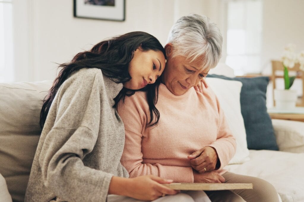 Elderly woman and daughter reflect sadly on a photograph