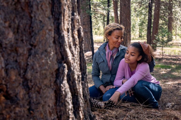 A mother and daughter honor their loved one at a memorial tree