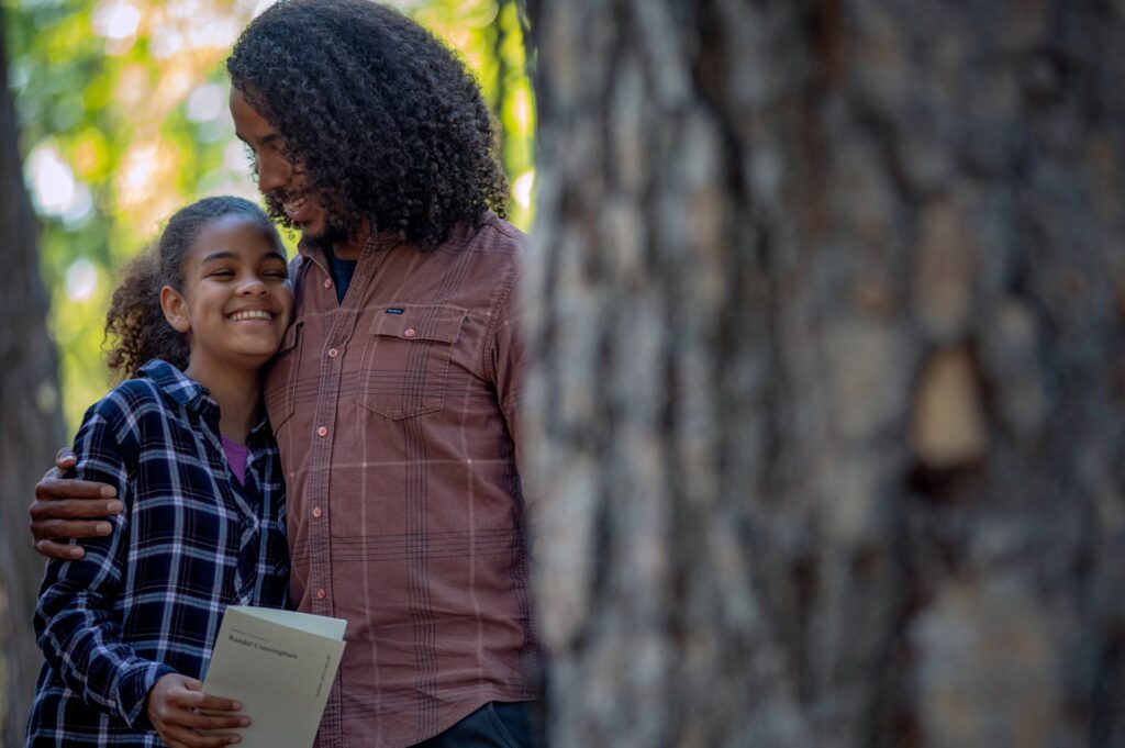 a young child mixes ashes with soil to plant at the base of a memorial tree