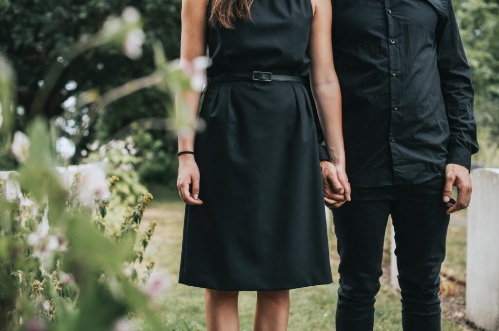 a couple holds hands at a memorial service