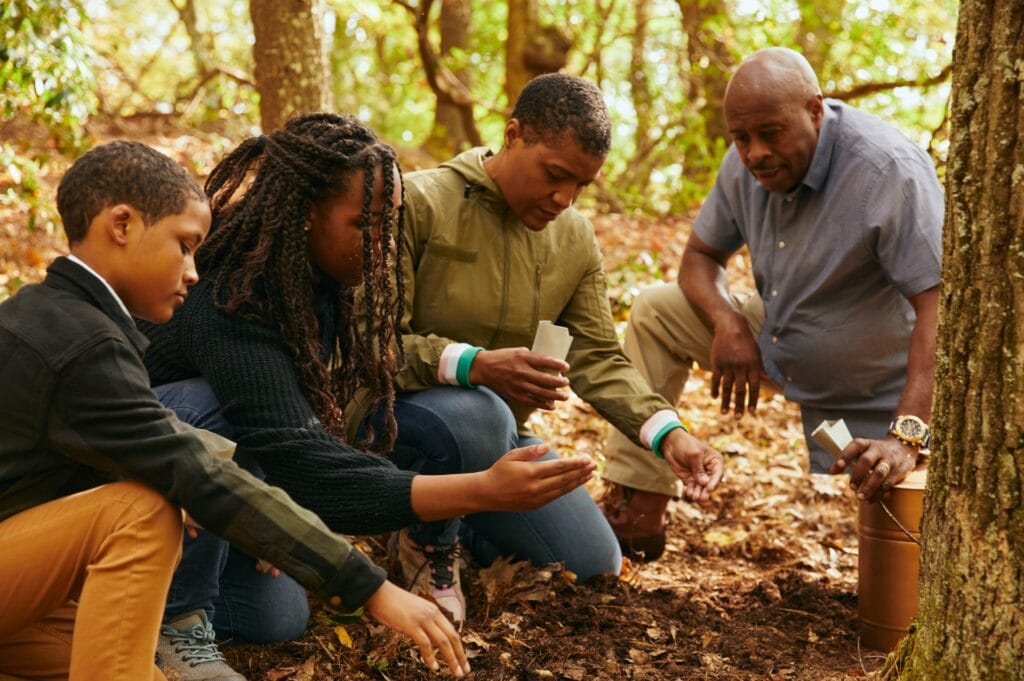 a family spreads seeds mixed with their loved ones ashes at the base of a memorial tree