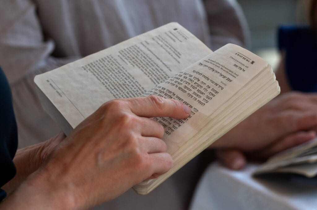 A man holds a Jewish prayer book while reciting a prayer