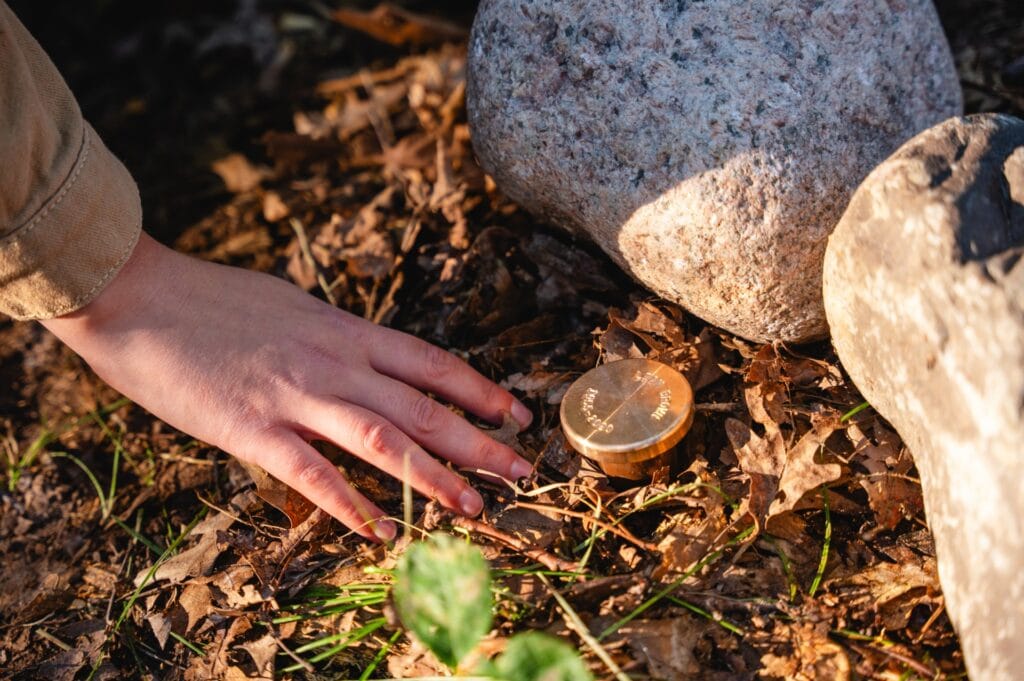 Closeup of a hand touching a memorial in a spreading grove for ashes of loved ones
