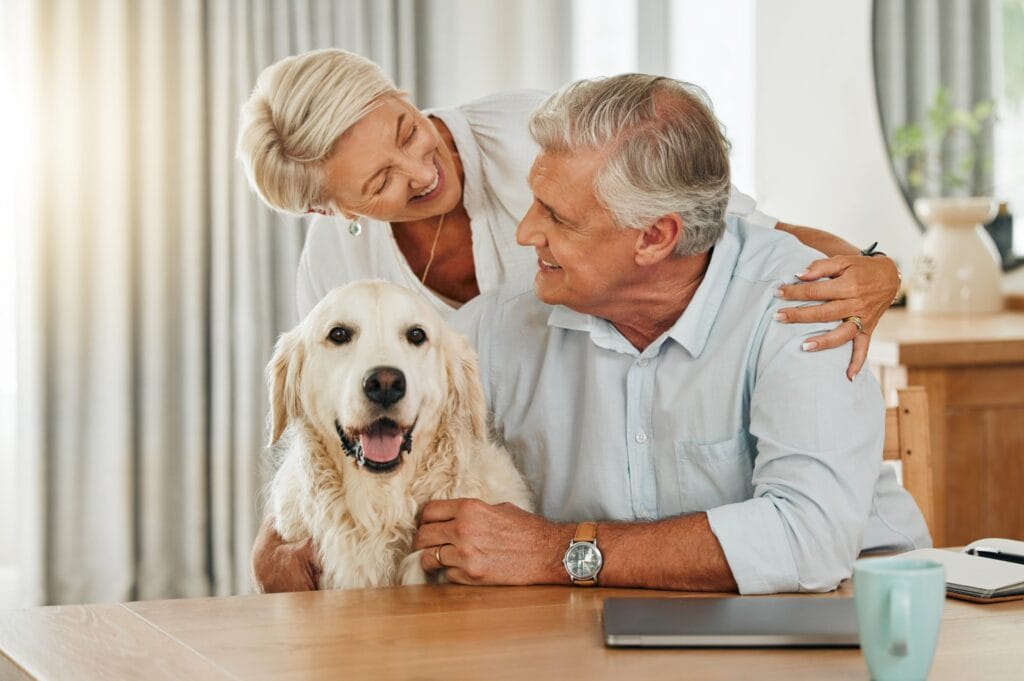 An elderly couple smiling with their dog, as they plan for end of life