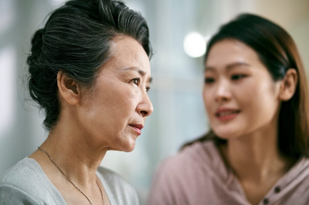 Woman comforts her mother as they begin writing an obituary for her father.