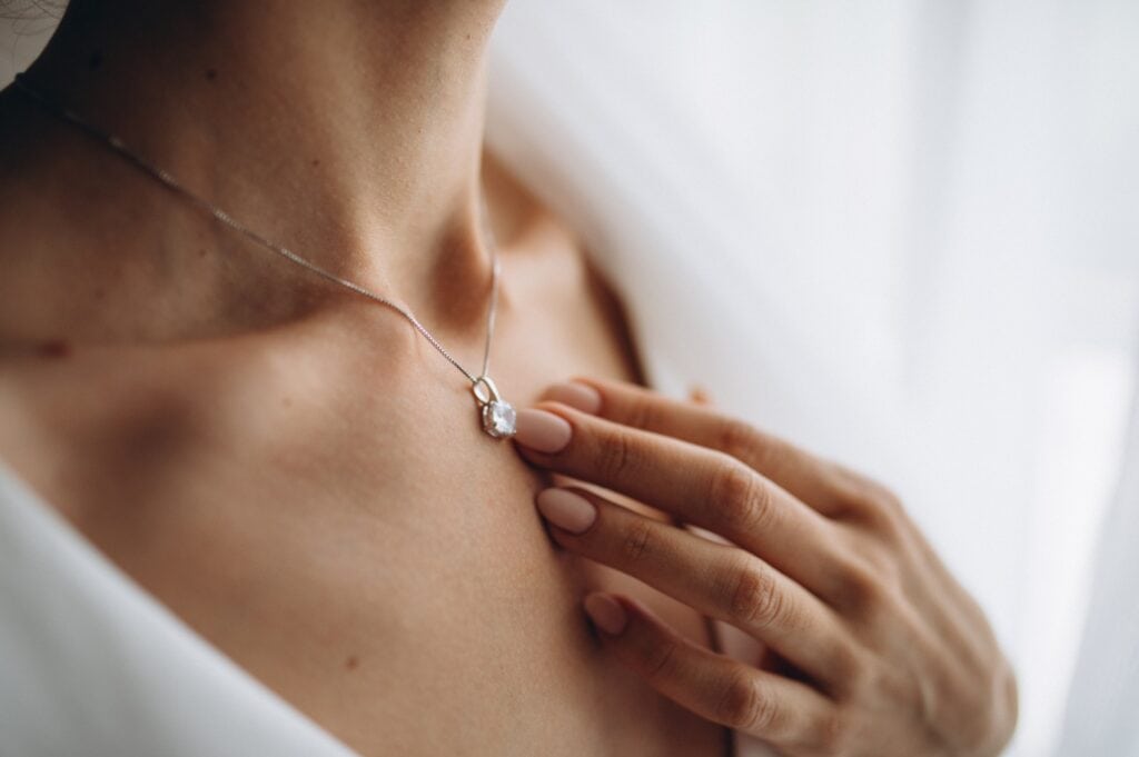 A woman’s hand rests on her necklace made from cremated remains of a loved one