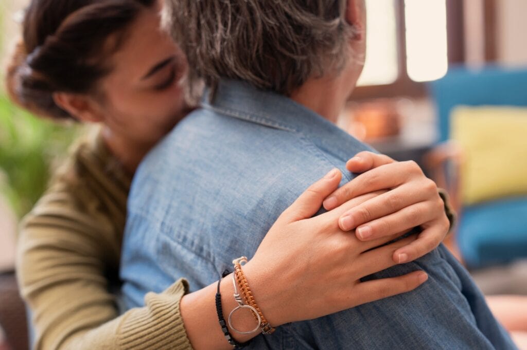 Woman places comforting hand on shoulder of her father