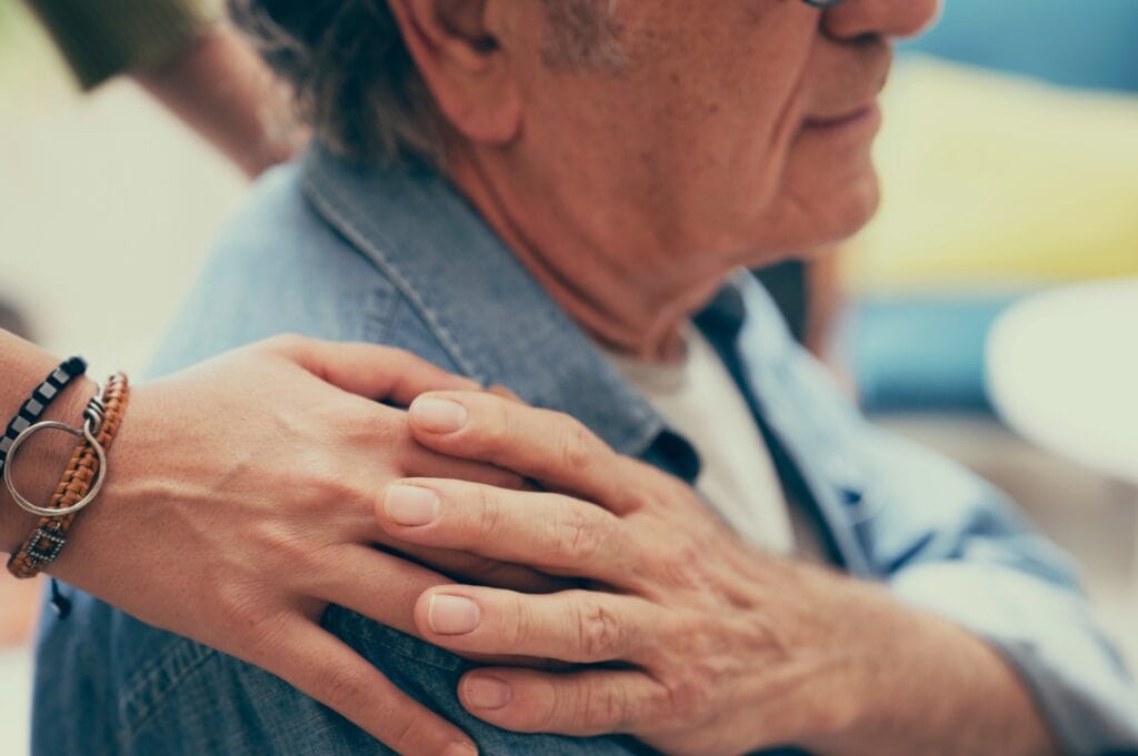 Woman places comforting hand on shoulder of her father