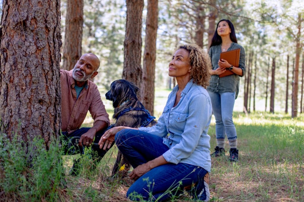 A man and woman sitting at the base of a memorial tree for their loved one