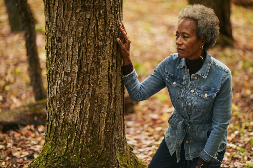 Woman sitting next to a memorial tree for her loved one