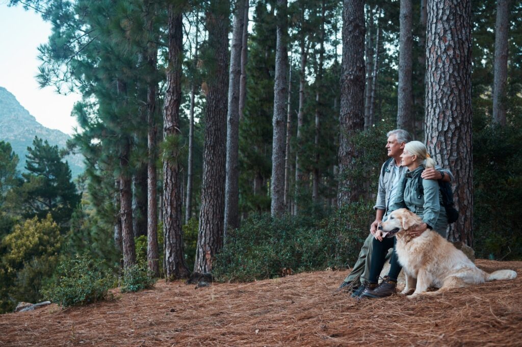 an elderly couple hiking with their dog