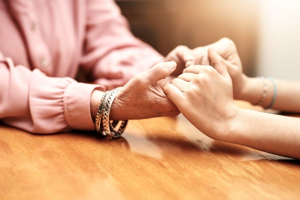 Close up of hands grasping in support for grief