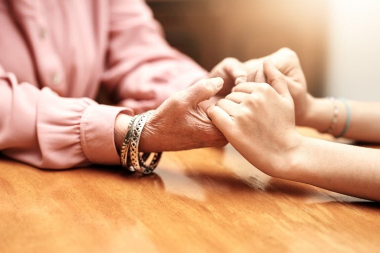 Close up of hands grasping in support for grief