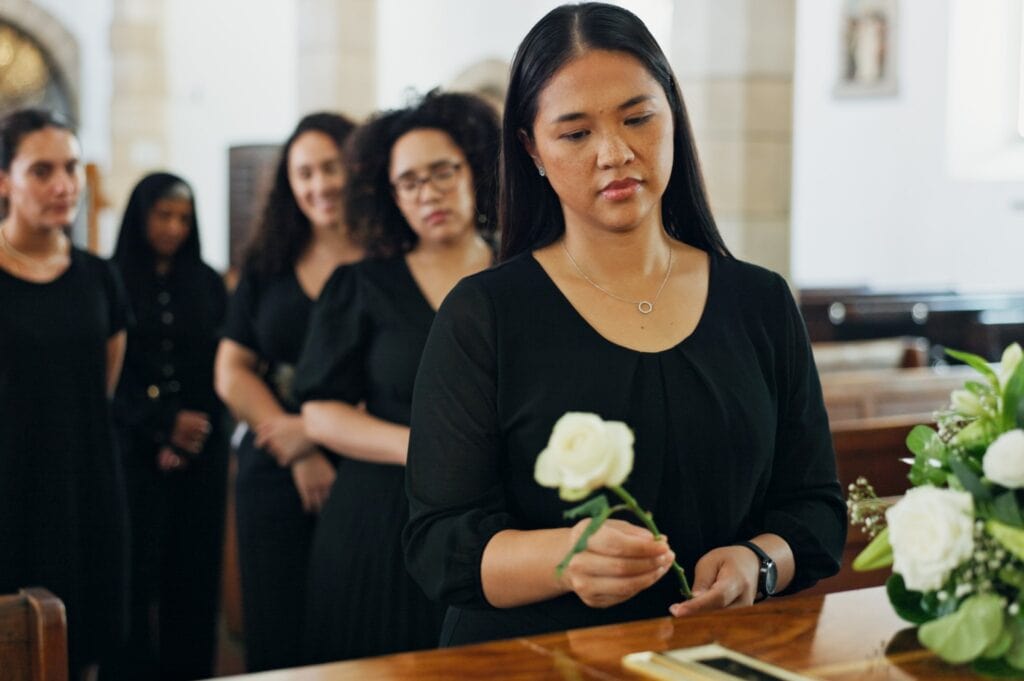 A woman places a white rose at a funeral