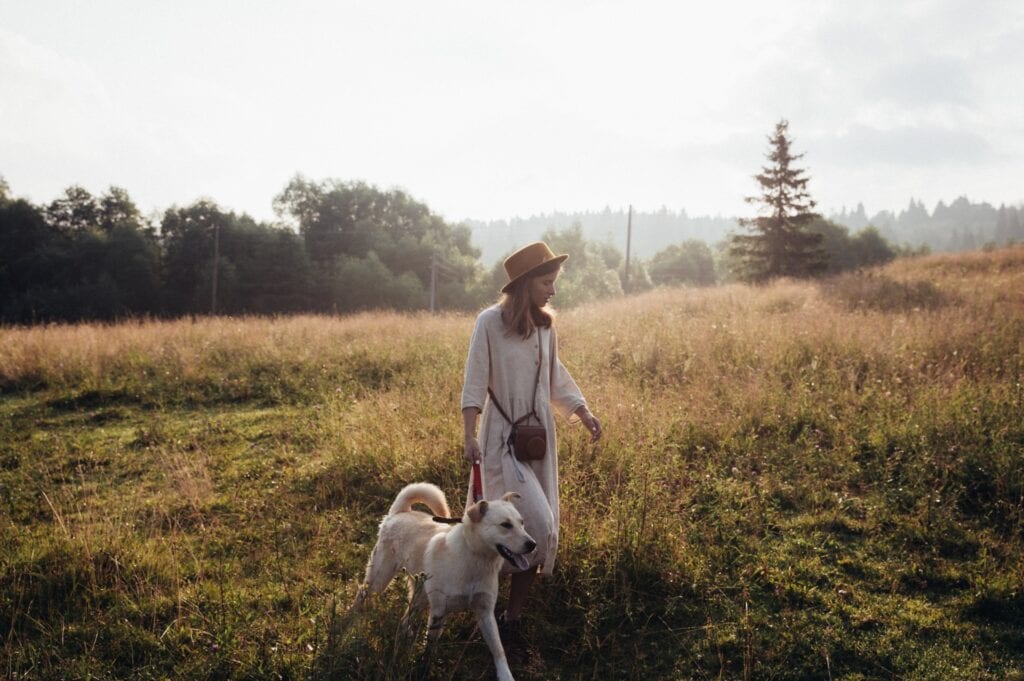 A woman and her dog in a field at sunset