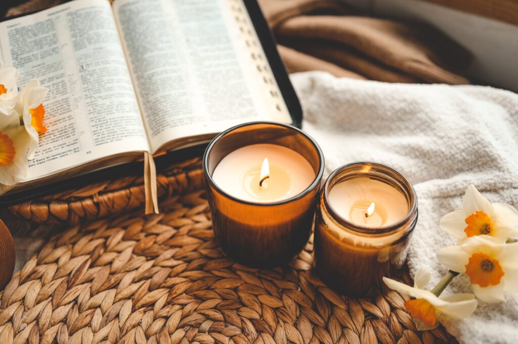 Warm lit candles by an open bible