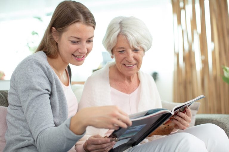two women looking at a photobook of memories of a deceased loved one