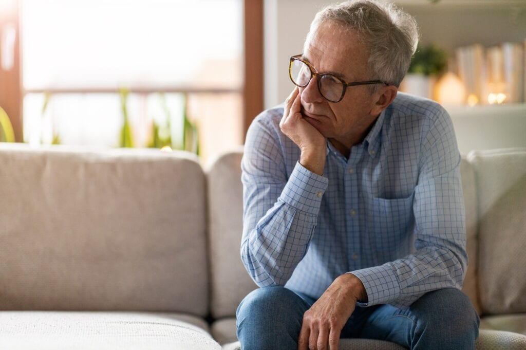senior man sitting on couch looking concerned