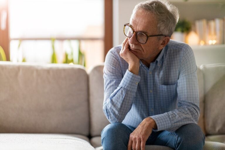 senior man sitting on couch looking concerned