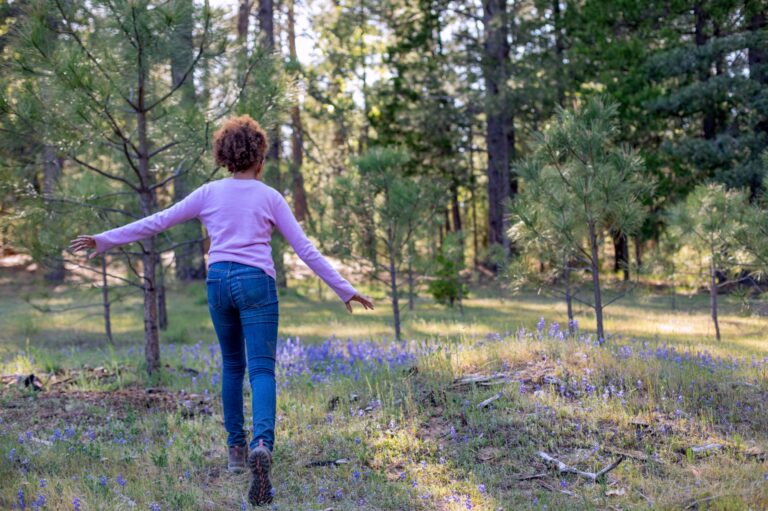 A girl running through a meadow with flowers in Yosemite Gateway Memorial Forest