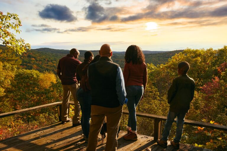 A family looks out at a sunset over a ridge at Litchfield Hills Memorial Forest