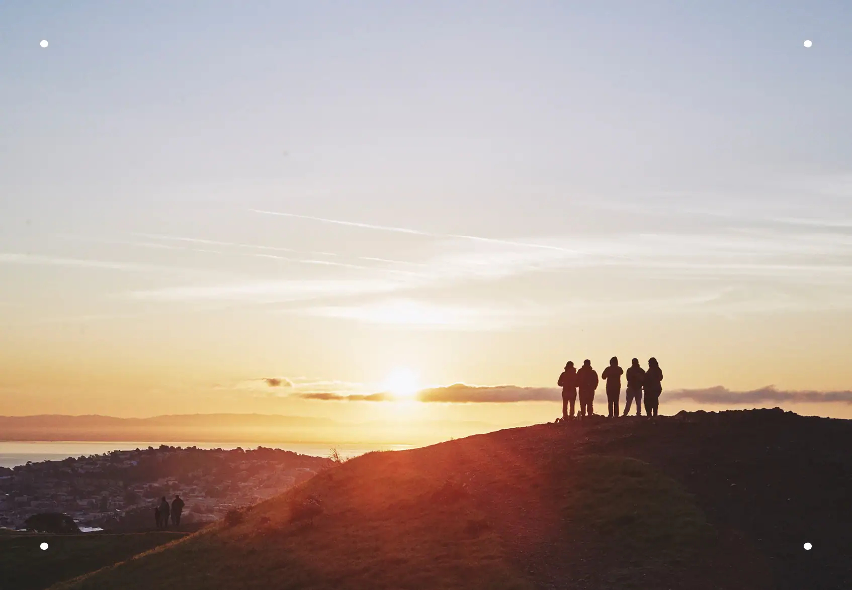 People watching the sunrise over the Oakland skyline, symbolizing renewal, connection, and trust in Everis’s carbon-neutral cremation services.