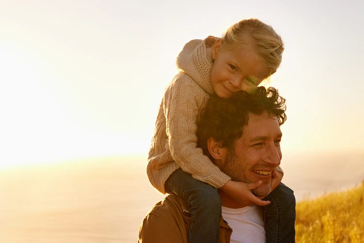 Father carrying his young daughter on his shoulders while walking in nature, symbolizing trust, love, and the compassionate support Everis provides to Berkeley families.